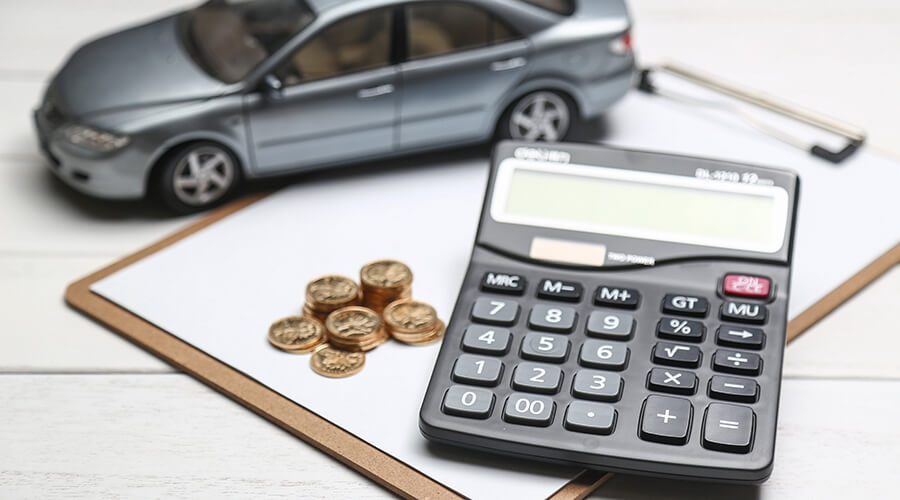 Automobil, kalkulator i kovanice na belom stolu